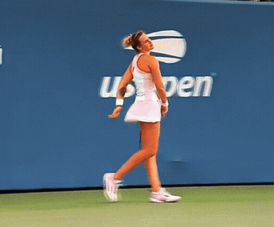 A Woman Walking On A Tennis Court In Front Of A Wall That Says Open GIF