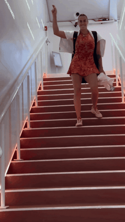 A Woman Walking Up A Set Of Red Stairs GIF