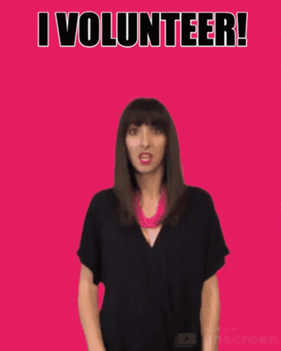 A Woman Waves Her Hand In Front Of A Pink Background With The Words I Volunteer GIF