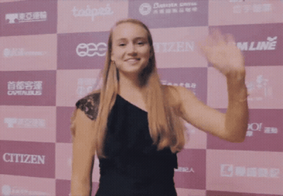 A Woman Waving In Front Of A Wall That Has Citizen On It GIF