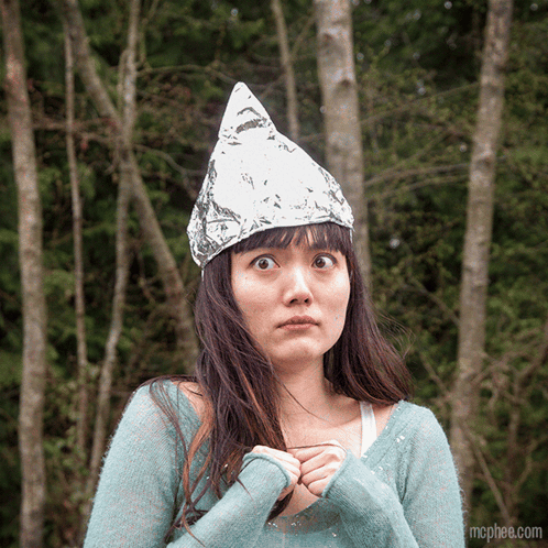 A Woman Wearing A Aluminum Foil Hat Is Standing In The Woods GIF