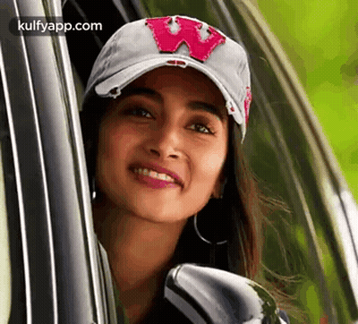 A Woman Wearing A Baseball Cap Is Looking Out Of A Car Window . GIF