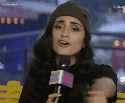 A Woman Wearing A Beanie And Holding A Microphone With The Hashtag Lollobr On The Bottom Right GIF