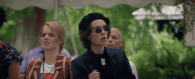A Woman Wearing A Beret And Sunglasses Stands In A Crowd GIF