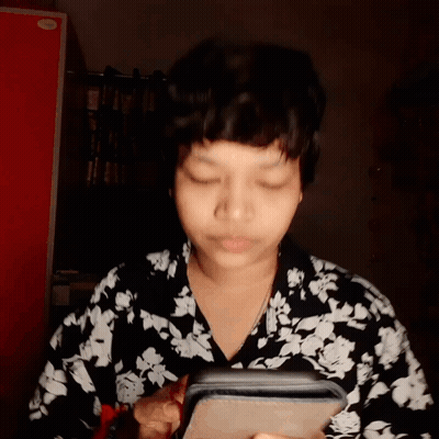 A Woman Wearing A Black And White Floral Shirt Is Looking At Her Phone GIF
