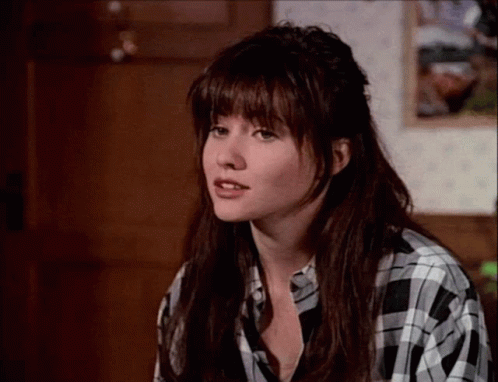 A Woman Wearing A Black And White Plaid Shirt Looks At The Camera GIF