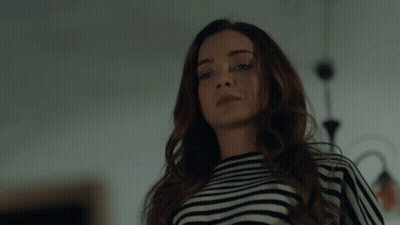 A Woman Wearing A Black And White Striped Shirt Is Looking At The Camera GIF