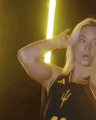 A Woman Wearing A Black And Yellow Jersey With A Trident On The Front GIF