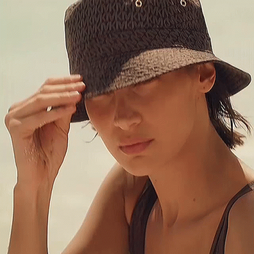 A Woman Wearing A Black Bucket Hat With The Letter M On It GIF