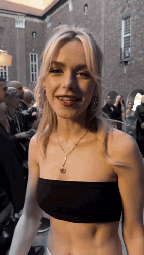 A Woman Wearing A Black Crop Top And A Gold Necklace GIF
