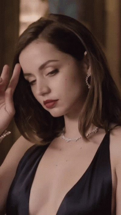 A Woman Wearing A Black Dress And A Necklace With Diamonds GIF
