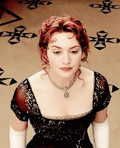 A Woman Wearing A Black Dress And White Gloves Is Looking Down GIF