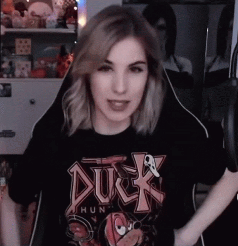 A Woman Wearing A Black Duck Hunt T-Shirt Is Sitting In A Chair In Front Of A Microphone . GIF