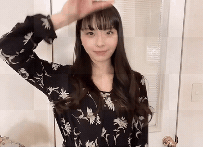 A Woman Wearing A Black Floral Shirt Is Standing In Front Of A Door . GIF