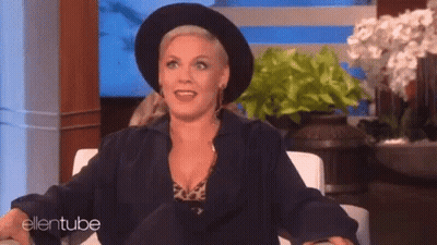 A Woman Wearing A Black Hat And A Black Jacket Is Sitting In A Chair On A Show . GIF