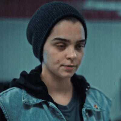 A Woman Wearing A Black Hat And A Denim Vest GIF