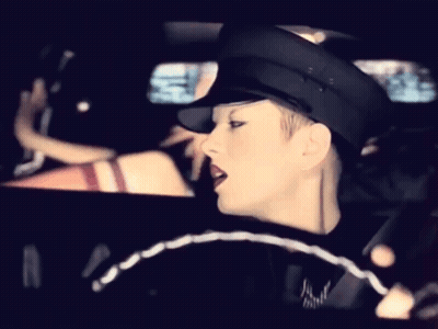 A Woman Wearing A Black Hat Is Driving A Car GIF