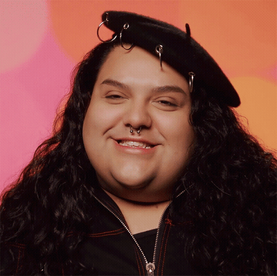 A Woman Wearing A Black Hat With Rings On It Smiles For The Camera GIF