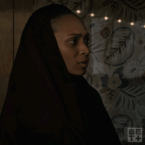 A Woman Wearing A Black Head Scarf Is Asking What Are You Talking About GIF
