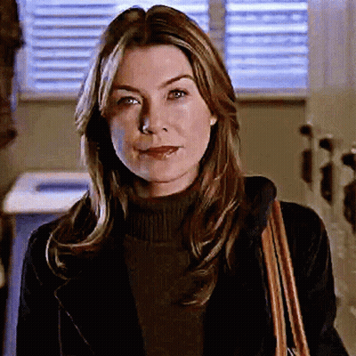 A Woman Wearing A Black Jacket And A Brown Purse Smiles GIF