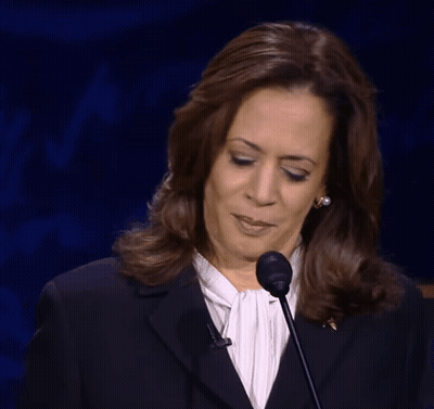 A Woman Wearing A Black Jacket And A White Shirt Stands In Front Of A Microphone Making A Funny Face GIF