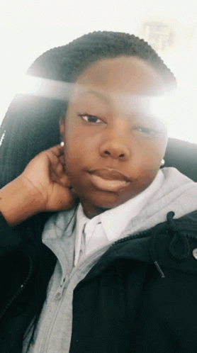 A Woman Wearing A Black Jacket And A White Shirt Takes A Selfie GIF