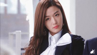 A Woman Wearing A Black Jacket And A White Shirt With A Bow GIF