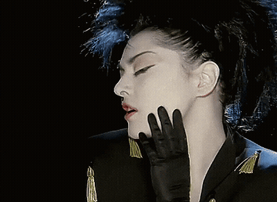 A Woman Wearing A Black Jacket Has Red Beads Hanging From Her Ears GIF