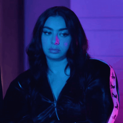 A Woman Wearing A Black Jacket With A Pink Stripe On The Sleeves Looks At The Camera GIF