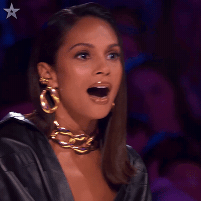 A Woman Wearing A Black Leather Jacket And Gold Hoop Earrings Has Her Mouth Open GIF