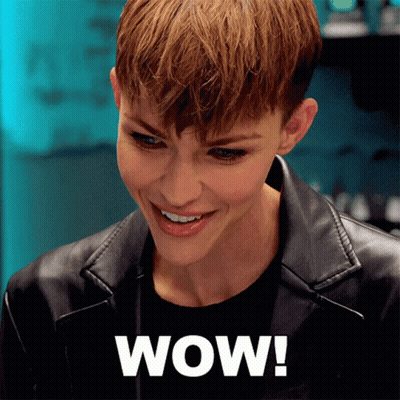 A Woman Wearing A Black Leather Jacket Is Smiling And The Word Wow Is On The Bottom Right GIF