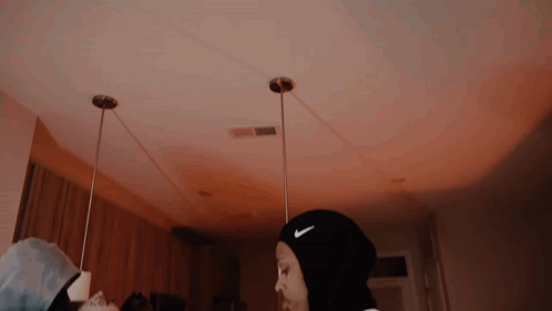 A Woman Wearing A Black Nike Headband Is Standing In A Dark Room . GIF