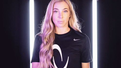 A Woman Wearing A Black Nike Shirt With A White Arrow On The Front GIF
