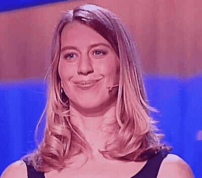 A Woman Wearing A Black Shirt And A Microphone Smiles For The Camera GIF