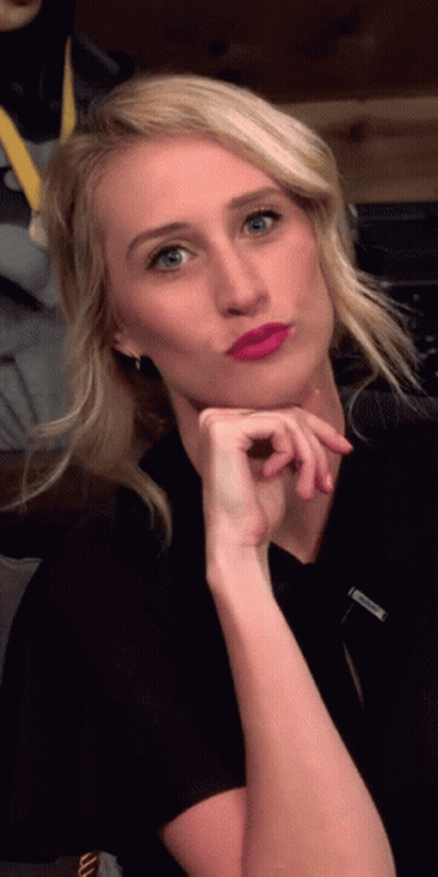 A Woman Wearing A Black Shirt And Pink Lipstick Is Making A Face GIF