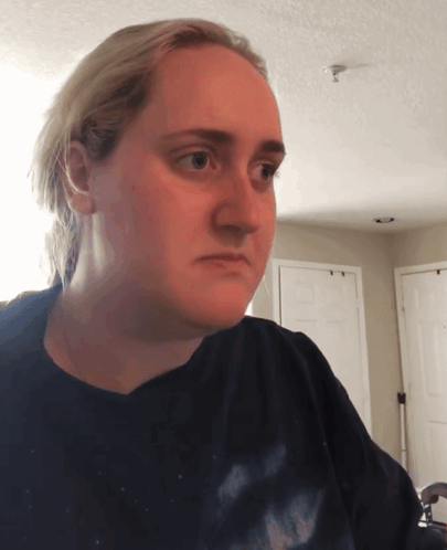 A Woman Wearing A Black Shirt Is Looking At The Camera GIF