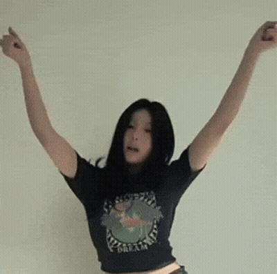 A Woman Wearing A Black Shirt That Says Dream Is Dancing With Her Arms Outstretched GIF