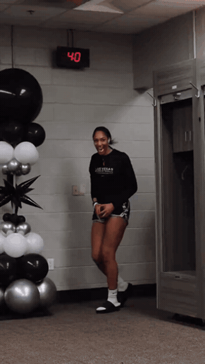 A Woman Wearing A Black Shirt That Says Las Vegas Basketball Is Standing In Front Of Balloons GIF