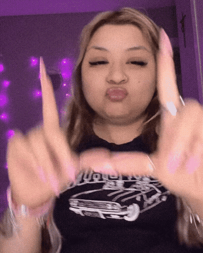 A Woman Wearing A Black Shirt With A Car On It Making A Funny Face GIF