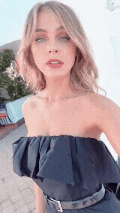 A Woman Wearing A Black Strapless Top Is Taking A Selfie With Her Eyes Closed GIF