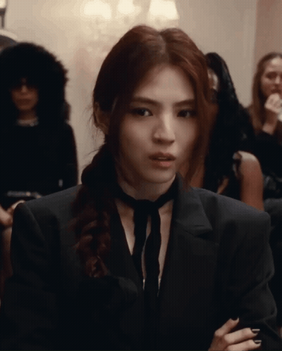 A Woman Wearing A Black Suit And Tie Is Looking At The Camera GIF