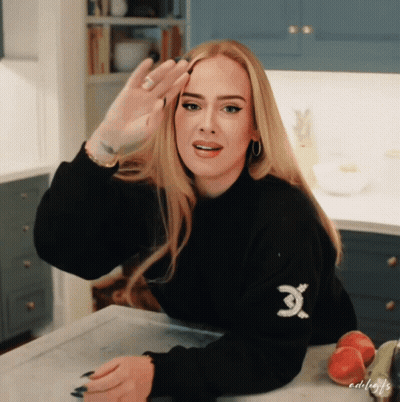 A Woman Wearing A Black Sweater With An X On The Sleeve GIF