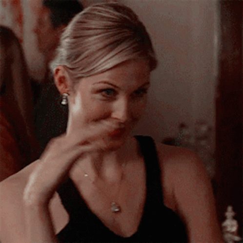 A Woman Wearing A Black Tank Top And A Necklace Is Making A Funny Face GIF