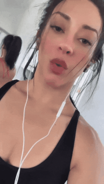 A Woman Wearing A Black Tank Top And White Ear Buds GIF