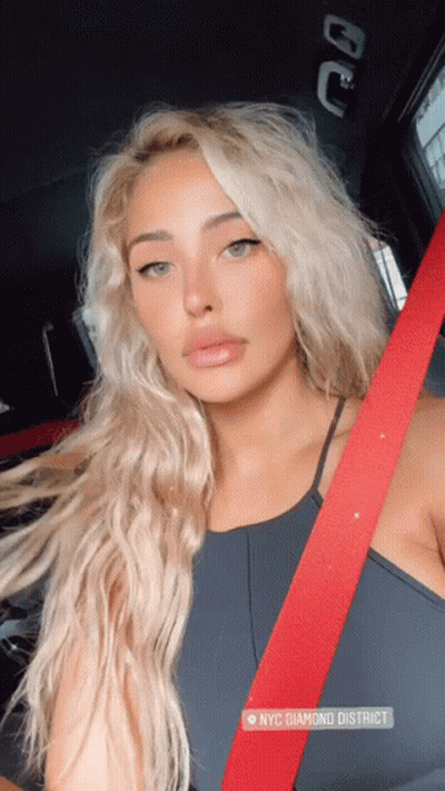 A Woman Wearing A Black Top And A Red Seat Belt Is Sitting In A Car In Nyc Diamond District GIF