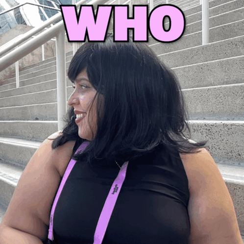 A Woman Wearing A Black Top And Purple Lanyard With The Word Who Above Her GIF