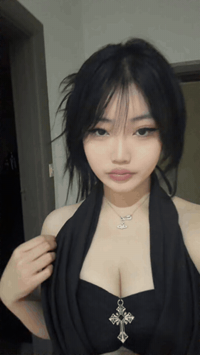 A Woman Wearing A Black Top With A Cross Necklace GIF