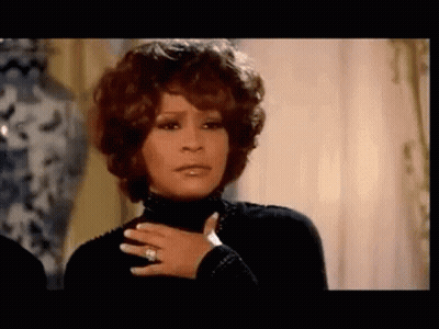 A Woman Wearing A Black Turtleneck And A Ring On Her Finger . GIF