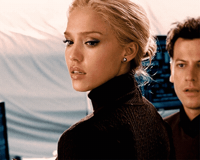 A Woman Wearing A Black Turtleneck Sweater And Earrings Stands Next To A Man GIF