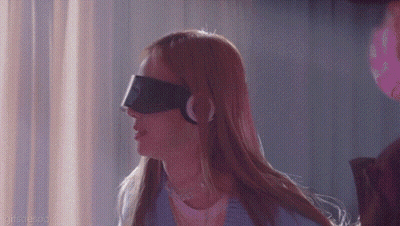 A Woman Wearing A Blindfold And Headphones Is Standing In A Dark Room . GIF